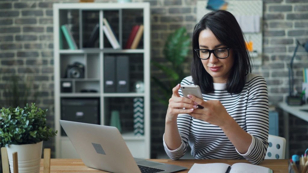 Why Intentional Living Supports Better Access To Modern Tools 1 a woman sitting at a desk looking at a phone